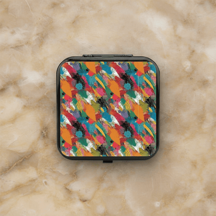 Black hardshell Nintendo Switch 24-slot game card case with colorful abstract brushstroke paint pattern in teal, orange, pink, black, and green