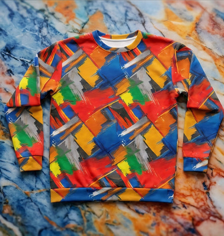 Brushstroke Riot sweatshirt by Dyles Mavis — crewneck sweatshirt with all-over print of crosshatched primary color paint brushstrokes in red, blue, yellow, green and grey, front flat lay on marble