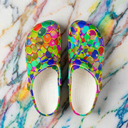 Colorful Mosaic EVA clog shoes by Dyles Mavis — lightweight clogs with all-over print of fractured mosaic tiles in green, blue, orange, pink and purple, top-down view with cream soles on marble