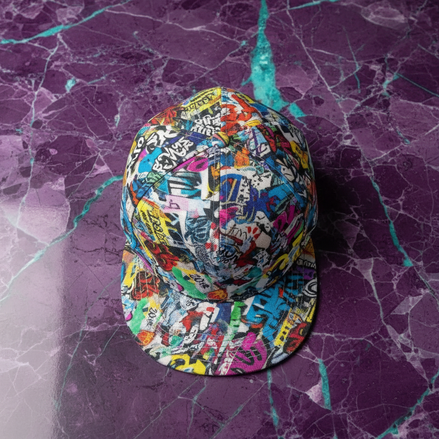 Street Collage Snapback with layered street art sticker and paste-up collage in blues, reds, and yellows on white base