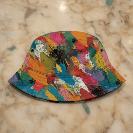 Paint Splash AOP Bucket Hat in one-size design with bold multicolor brushstroke and paint splash print in orange, teal, pink, red, and yellow, top-down and side view