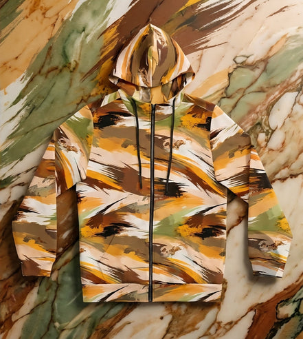 Autumn Brushstroke Zip Hoodie women's full-zip in warm ochre, caramel, olive, rust, and cream sweeping brushstroke pattern with drawstring hood, flat lay on marble