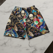 Dearly Departed Basketball Shorts in black performance fabric with skull, skeleton hand, and jewel mosaic collage in cream, teal, red, gold, and blue, flat lay on marble