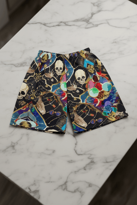 Dearly Departed Basketball Shorts in black performance fabric with skull, skeleton hand, and jewel mosaic collage in cream, teal, red, gold, and blue, flat lay on marble